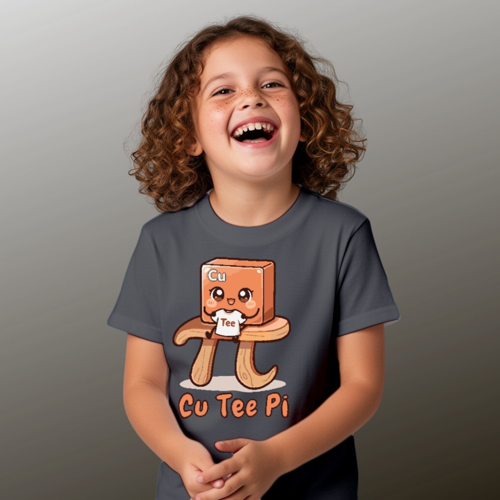 girl wearing charcoal Cu Tee Pi kids science t-shirt with cute copper cube sitting on pi symbol table