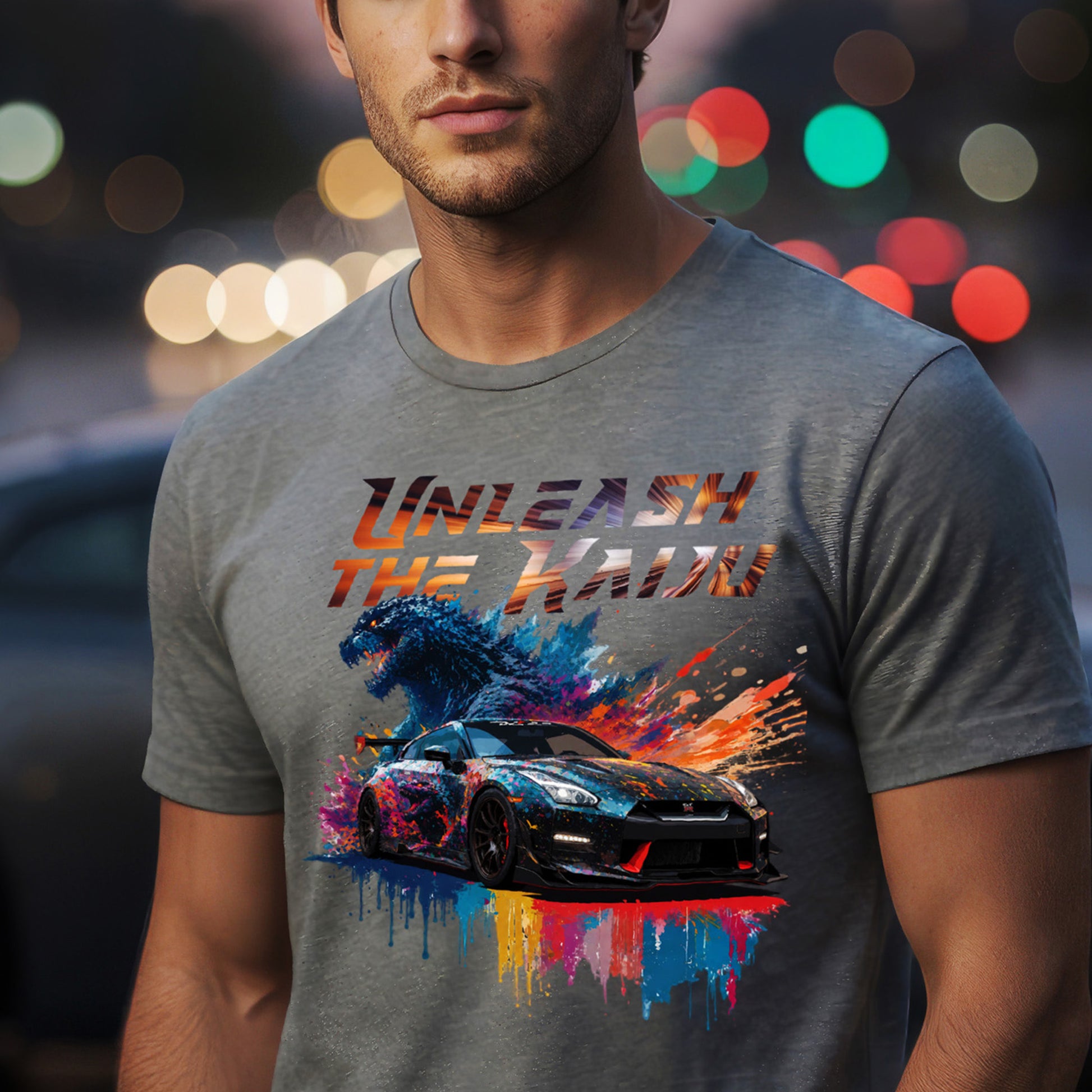 Man wearing a gray t-shirt with nissan gtr35 with godzilla design and text 'UNLEASH THE KADO' against a blurred lights background