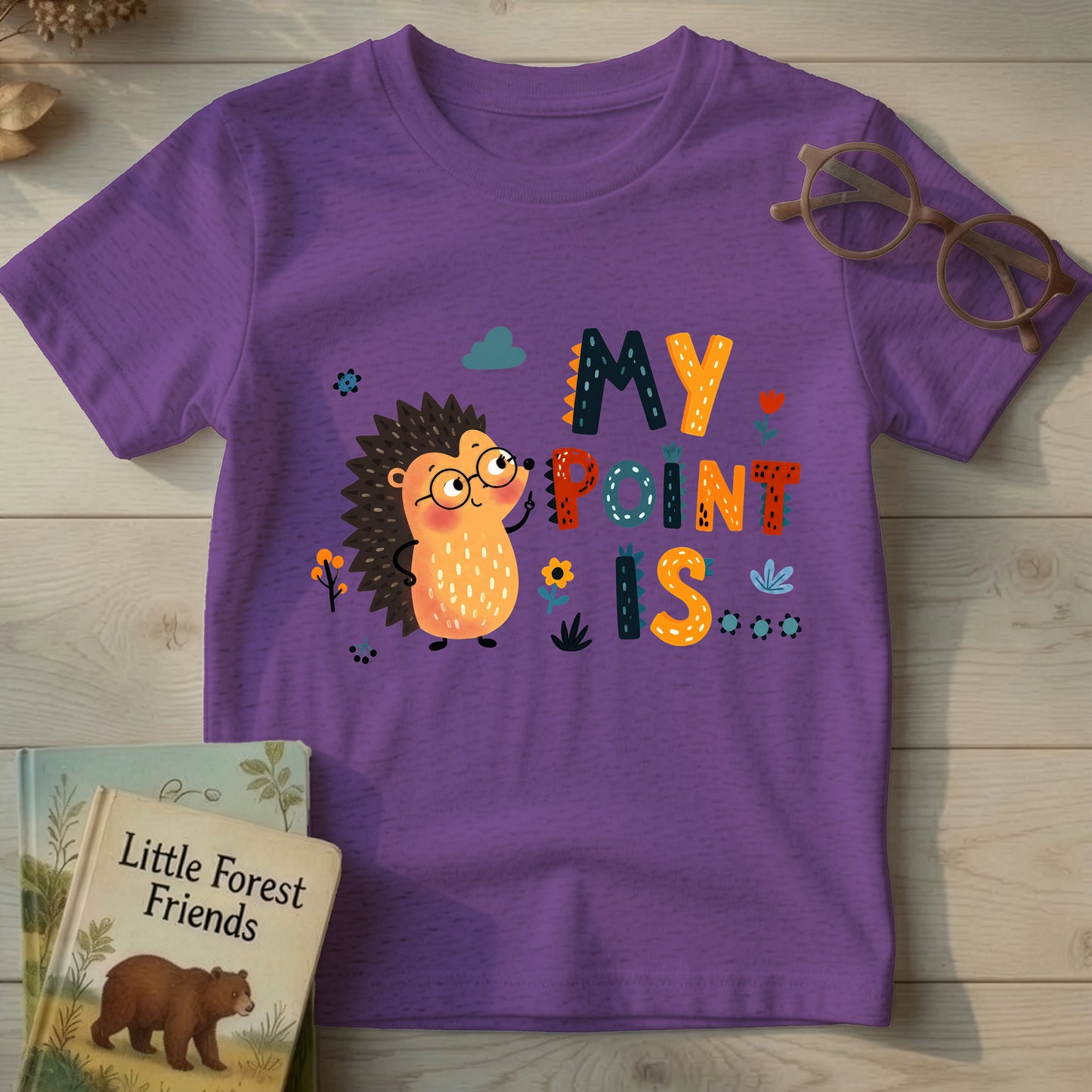 Purple heather kids t-shirt with cartoon hedgehog in glasses and "My Point Is" quill-textured typography, flat lay on wood background